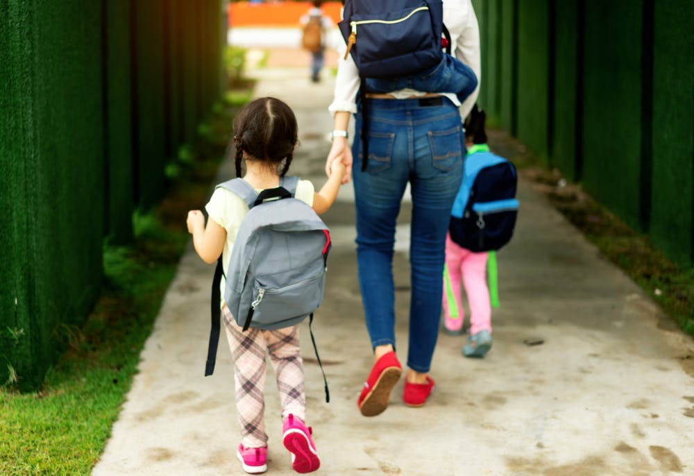 Parent and two small children with backpacks