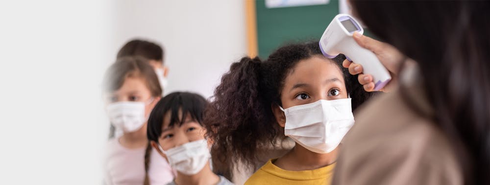 Elementary students with face masks getting temperature check.
