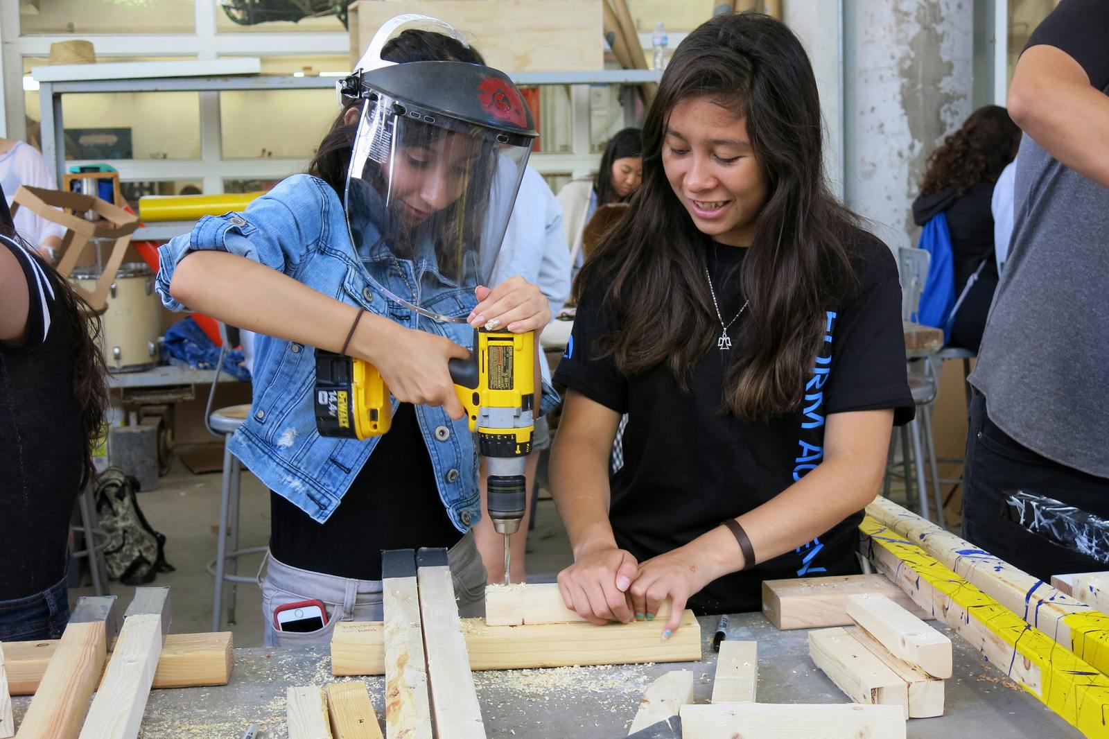 UCLA Community School students Vanessa Morales (at left) and Leslie Roman learn to drill holes in wood to create stilts as part of the &quot;Walking Taller&quot; project at the FORM Academy.