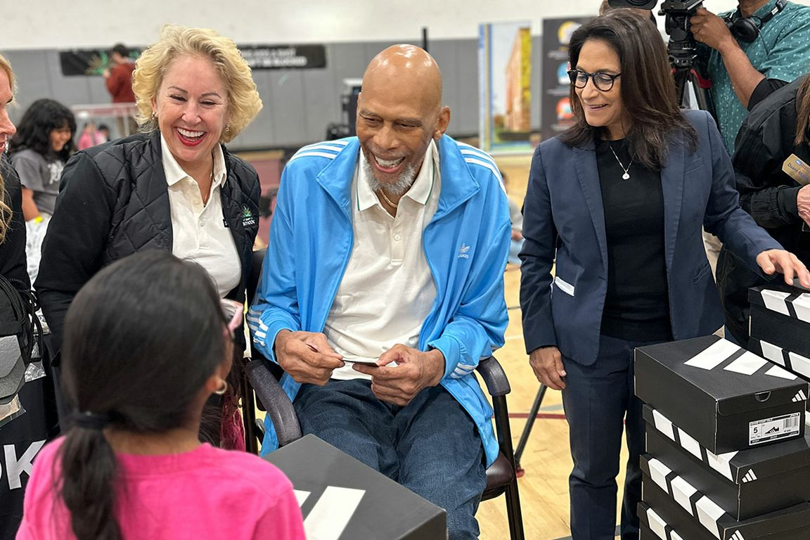 Kareem Abdul-Jabbar and Dean Tina Christie passing out shoes at UCLA Community School